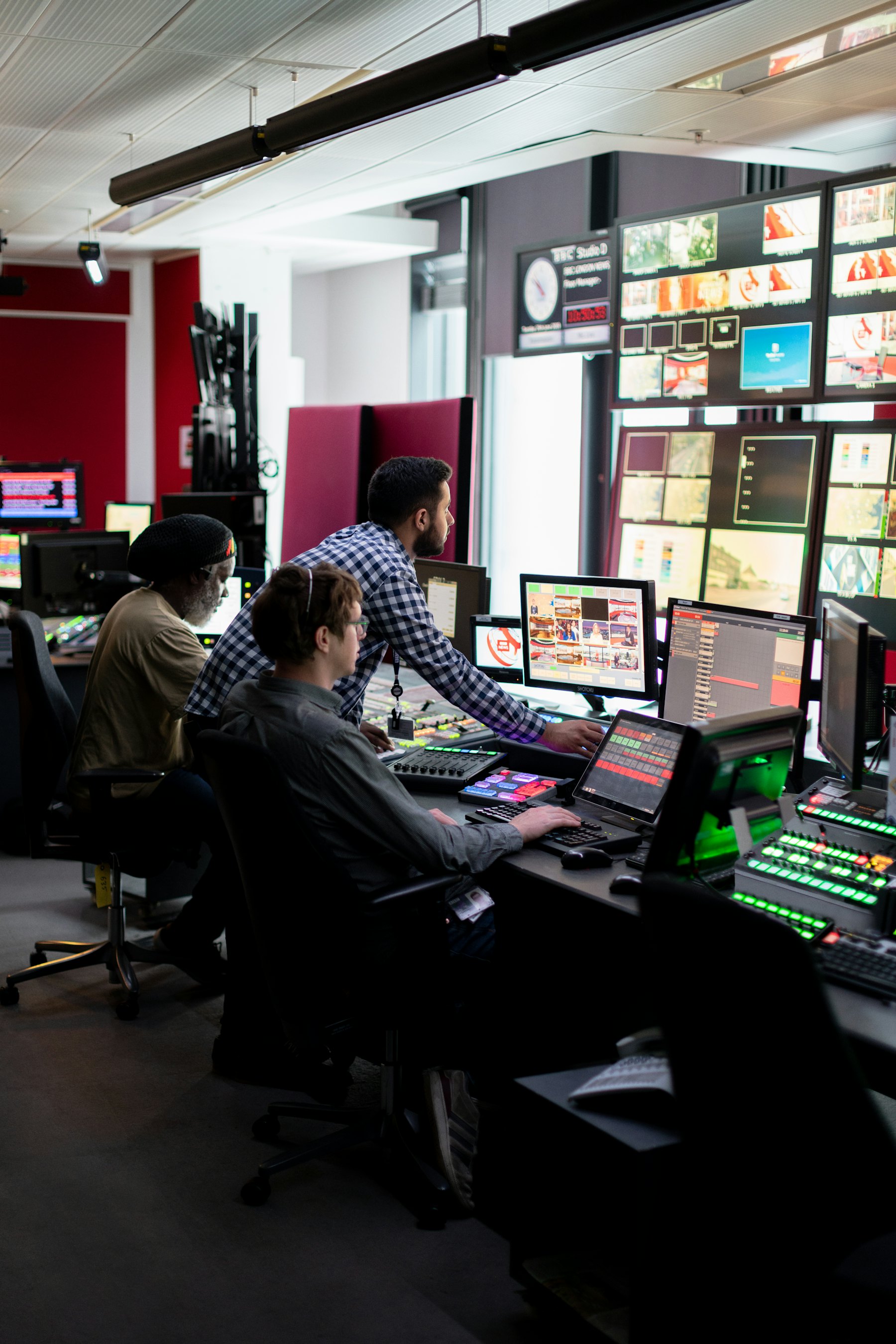 Operators working a broadcast control room wall of monitors