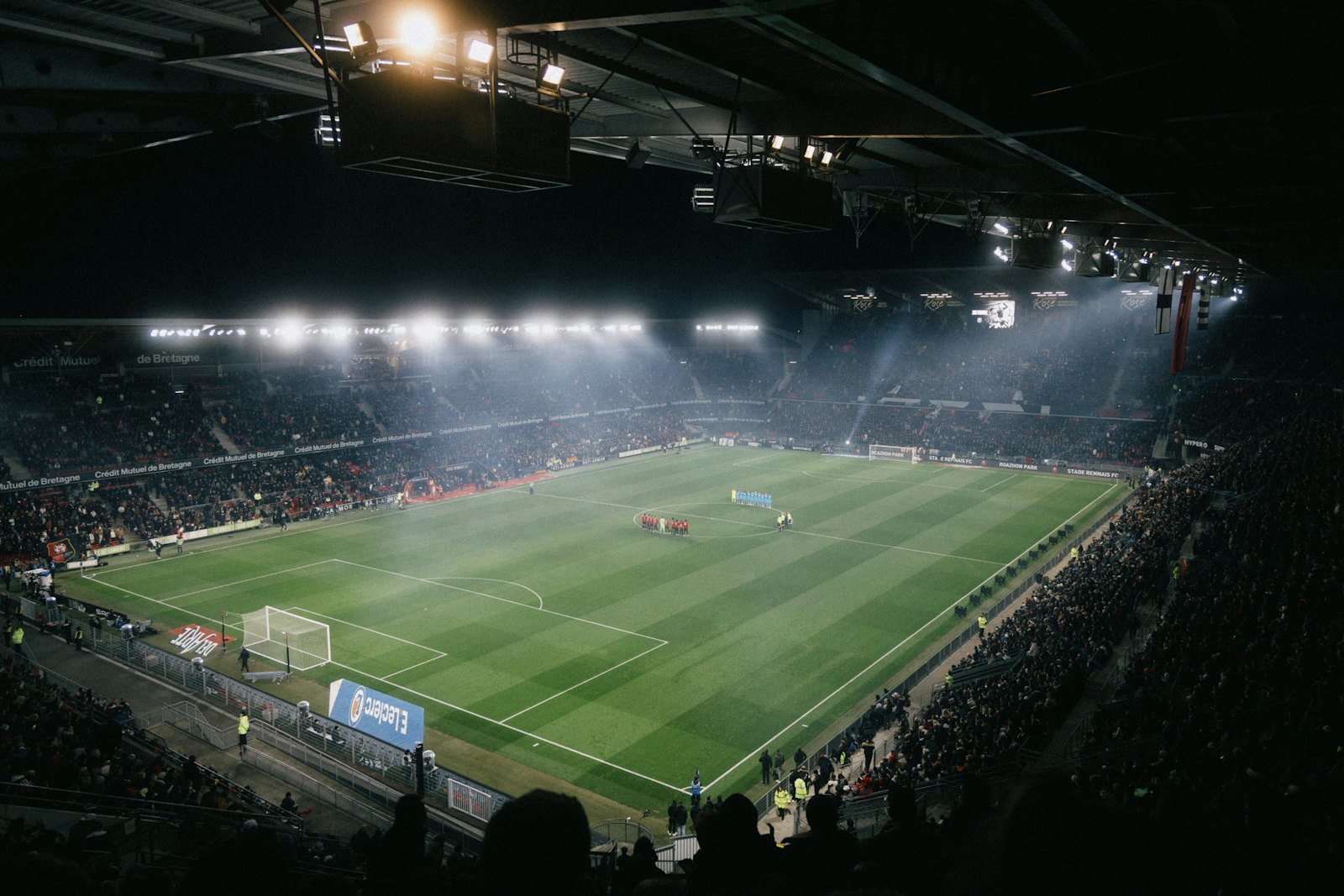 A full stadium under floodlights at night