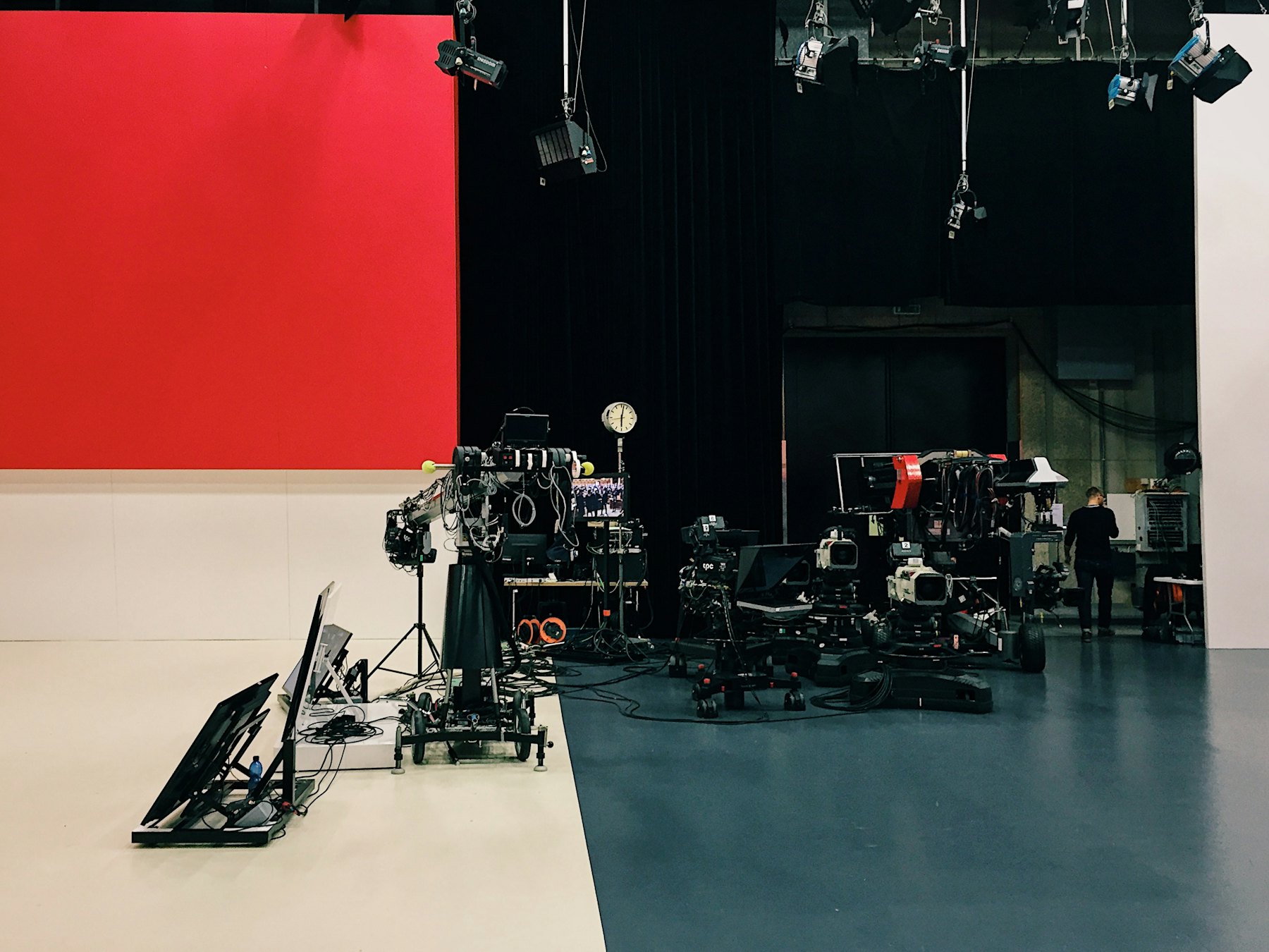 A studio floor with camera rigs set against a red wall